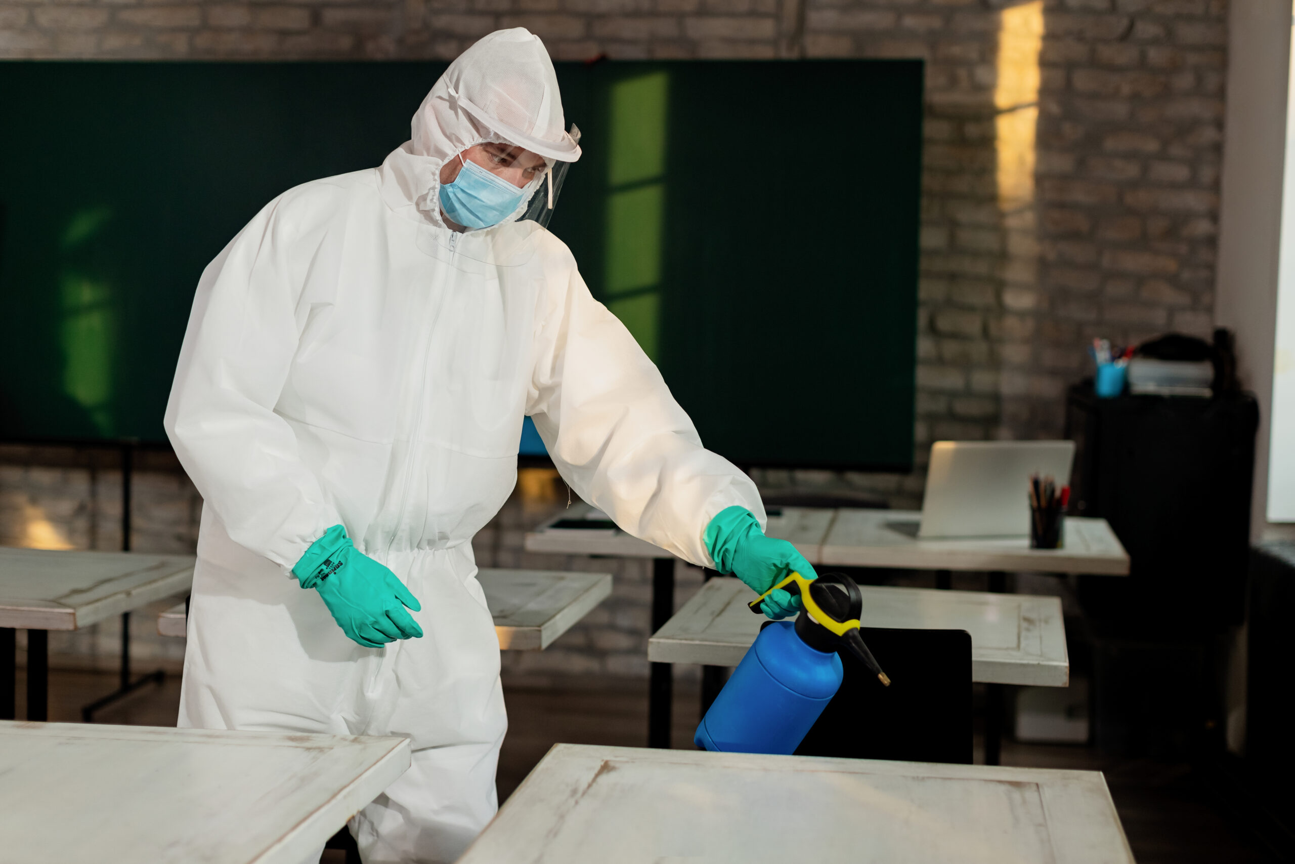 Person in white suit spraying pest control under the table | Rat Trap Experts Hackney, London